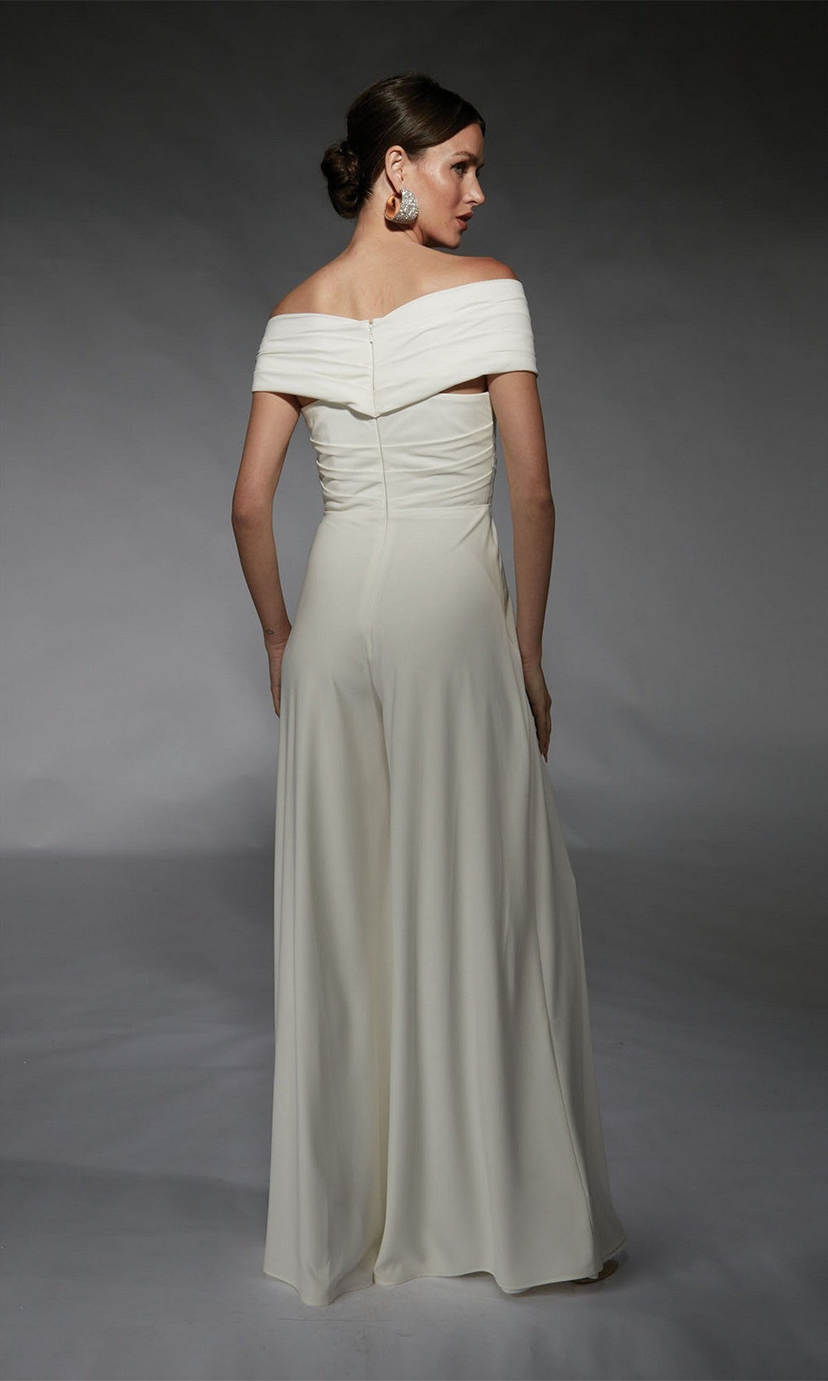 A woman faces away from the camera against a plain gray background, wearing the Alyce 70067 long formal dress.